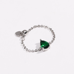 Détail de la bague ajustable avec pierre poire verte et breloque cœur en finition argent