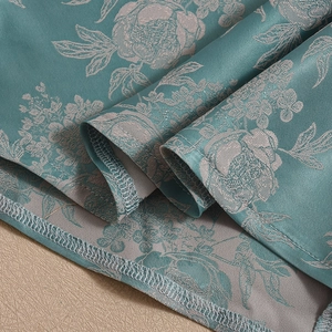 Detail of teal satin dress showing floral texture and high-quality stitching craftsmanship