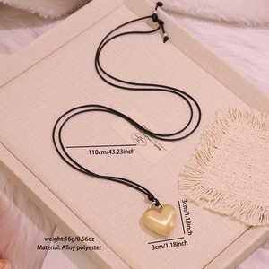 Detail showing the matte gold heart pendant with dimensions and black cord necklace