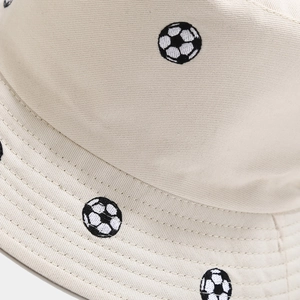 Vue détaillée d'un chapeau bob en coton crème avec broderie de football noire et blanche