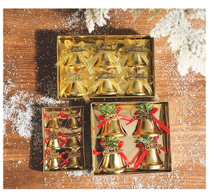 Close-up of gold Christmas bell ornaments with red ribbons on a festive wooden table