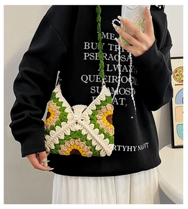 Mirror selfie showing a handmade crochet sunflower shoulder bag with floral knit patterns