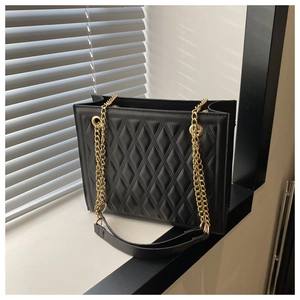 Detail of black quilted leather shoulder bag with elegant golden chain strap and texture