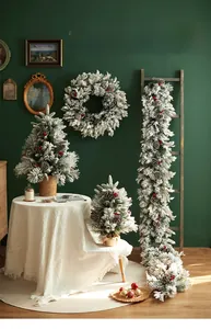 Close-up of frosted Christmas wreath and mini trees with pine cones and red berries