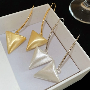 Detailed view of brushed metal triangular earrings in gold and silver finishes