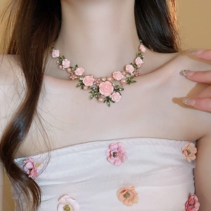 Detail of floral necklace featuring pink roses, green leaves, pearls, and crystals
