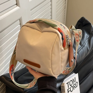 Beige oxford crossbody bag with decorative floral wide shoulder strap in indoor setting