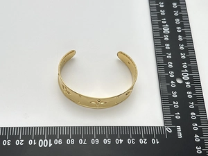 Close-up showing width measurement of gold cuff bangle with embossed floral textures