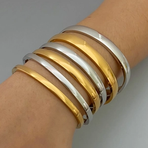 Minimalist titanium steel bangles in gold and silver finish on model's wrist