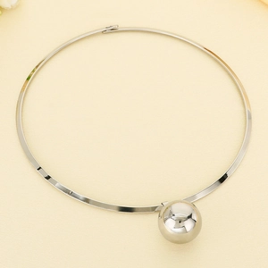 Polished silver stainless steel collar necklace with a hollow sphere pendant on beige fabric