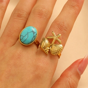 Close-up of vintage gold rings with large oval turquoise and detailed starfish sea shell motifs