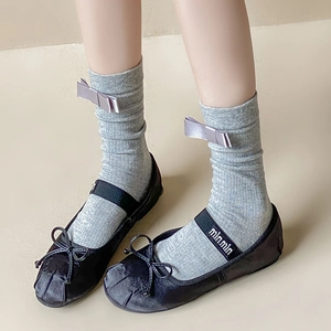 Detail of grey ribbed socks with light purple bows paired with black Mary Jane shoes