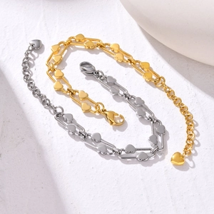 Detailed macro view of heart-shaped links and lobster clasp on steel and gold chain