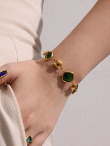 Macro detail of 18K gold plated bracelet with emerald green glass stones and matching rings