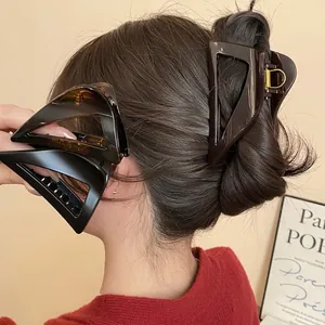 Three large geometric triangle hair claws in tortoiseshell and solid brown resin finishes