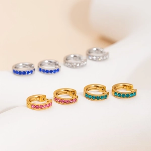 Elegant gold and silver hoop earrings set with colorful gemstones on a white stand