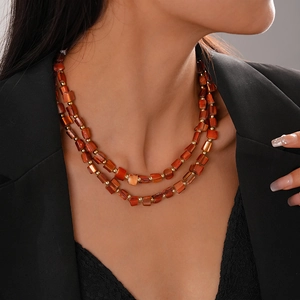 Close-up of double-layered beaded necklace with irregular red beads and gold accents
