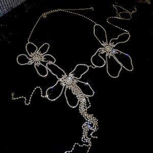 Detail of flower body chain with crystal rhinestones and layered tassels on black background