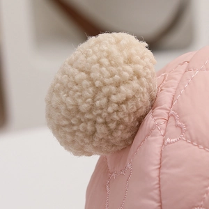 Detail der Wintermütze für Kinder mit gestepptem Herzmuster und flauschigem Bommel