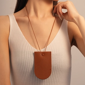 Close-up of a brown leather key pouch necklace with detailed stitching and snap closure