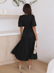 Detail of puffed short sleeves and layered tiered hemline on a black midi dress back view