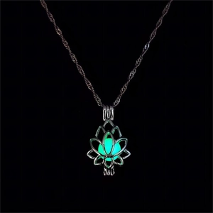 Détail du collier médaillon lotus argenté avec perle luminescente verte dans le noir
