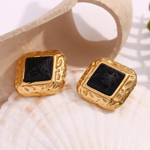 Macro detail of vintage gold-plated square studs with black acrylic and water droplets