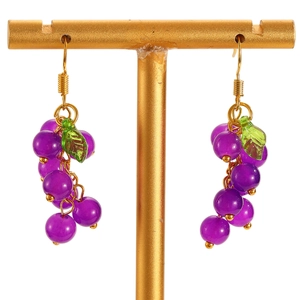 Detail of purple grape pendant earrings with green leaves on a gold jewelry stand