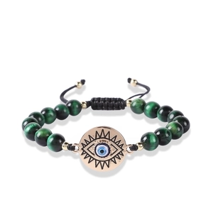 Detail of green tiger eye beads and golden evil eye charm on hand-woven bracelet