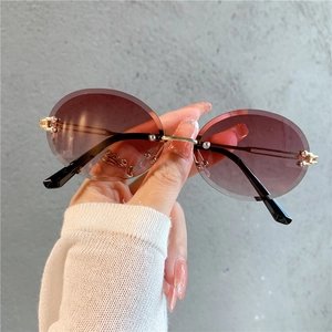 Détail de lunettes de soleil ovales sans monture, verres dégradés marron et pont doré
