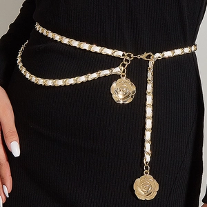 Détail d'une chaîne de taille en métal doré avec similicuir blanc et pendentifs roses