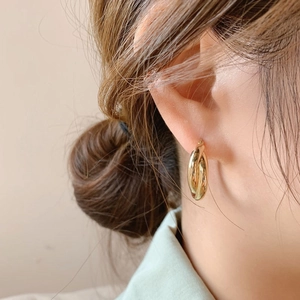 Modern double-layered geometric gold twist earrings shown on model for stylish wear