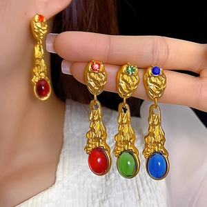 Lava style gold earrings with red green and blue gemstones shown in detail