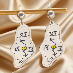 Detalle macro de pendientes de reloj derretido plateados inspirados en el arte de Dalí