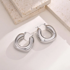 Detailed close-up of hollow silver U-shaped titanium steel earrings on a stone surface