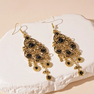 Macro detail of vintage gold filigree earrings with black gemstones on stone surface