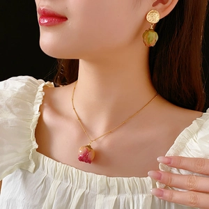 Preserved rose jewelry set with pink flower necklace and green bud earrings worn by model