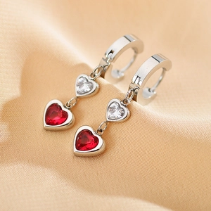 Dettaglio macro di orecchini a cuore in argento con cristalli rossi e bianchi
