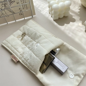 Macro detail of white quilted cosmetic bag featuring exquisite rabbit embroidery and snap closure