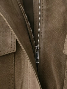 Détail de la fermeture éclair métallique et de la poche sur une veste en daim marron