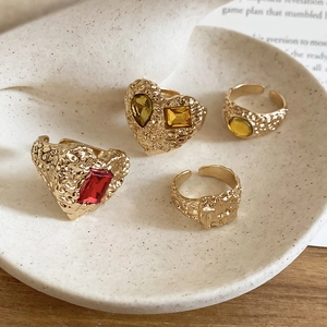 Detail of vintage gold heart ring set with colorful gems on a ceramic plate