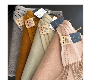Close-up of four colored 100% Australian wool scarves with fringes and stitched edges
