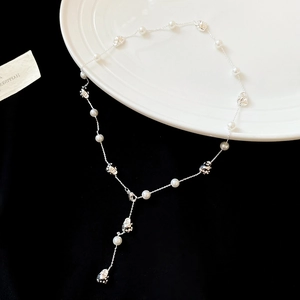 Detailed view of silver chain necklace with irregular pearls and metallic beads on black velvet