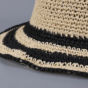 Close-up of hand-woven straw texture and beige-black stripes on a sun hat