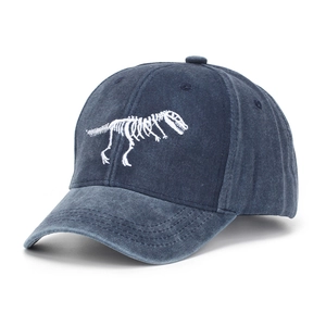 Detail of white dinosaur skeleton embroidery on washed navy denim baseball cap