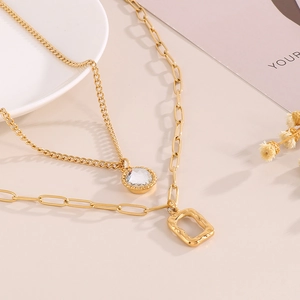 Detail of double-layer gold necklace with sparkling round and geometric pendants