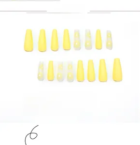 Detail view of yellow matte coffin nails featuring white daisy floral nail art designs