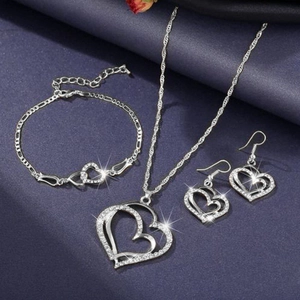 Flat lay of heart-shaped silver necklace, bracelet, and earrings with white rhinestones