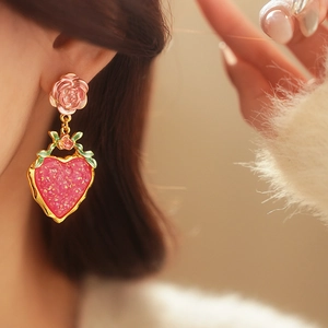 Detail of pink rose and red heart strawberry-textured earrings with gold glitter accents