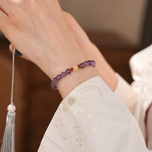 Detail of amethyst beaded bracelet on model wrist with elegant oriental embroidery